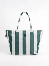Bolso tipo tote grande, resistente al agua, con diseño de rayas verticales rojas y blancas. Cuenta con asas largas de hombro, cierre superior y parche de cuero con logo grabado. Incluye neceser transparente a juego con base y detalles a rayas.