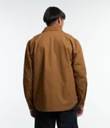 Camisa de manga larga confeccionada en sarga de algodón color verde menta, con cuello inglés y cierre frontal de botones negros. Presenta dos bolsillos de parche con solapa en el pecho y puños con botones.