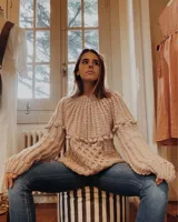 Sweater de lana merino color marfil, tejido a mano con puntos combinados de trenzas, bodoques y punto panal, de mangas largas y silueta relajada.