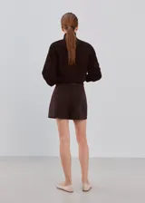 Minifalda marrón oscuro de corte recto, con diseño liso y cierre cruzado simulado.