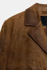 Abrigo largo de piel 100%, color marrón con efecto desgastado o envejecido. Presenta cuello solapa de muescas, manga larga, cierre frontal de botones y bolsillos de plastrón delanteros.