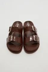 Sandalias planas de mujer con doble tira ancha en el empeine, hebillas metálicas plateadas y textura símil cocodrilo.