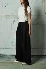 Pantalón de vestir negro de corte ancho y tiro alto, con pinzas frontales y cierre oculto.
