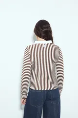 Remera de manga larga a rayas verticales verdes y blancas, con cuello polo y cierre frontal de botones. Presenta un diseño ajustado al cuerpo.