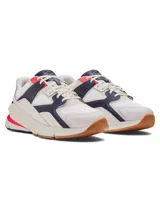 Championes Under Armour modelo Forge 96 Lthr Rissue, de diseño retro inspirado en los años 90. Combinan parte superior de malla y cuero en color blanco, con detalles en azul marino, toques de rosa fuerte y talón dorado. Cuentan con una entresuela robusta y suela de goma.
