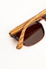 Lentes de sol polarizados con armazón transparente y patillas de madera, con cristales oscuros.