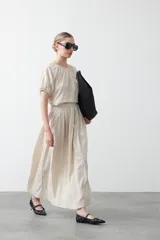 Falda larga plisada color marrón, de silueta amplia y caída fluida.