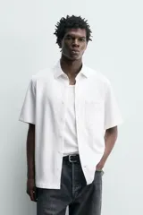Camisa azul marino de corte regular fit confeccionada en tejido fluido de algodón y lino, con cuello solapa, manga corta, bolsillo aplicado en el pecho y cierre frontal con botones.