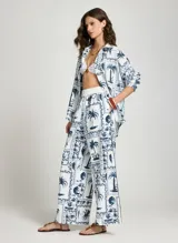 Pantalon ancho de tiro alto de Le Lis Blanc con estampado de palmeras y motivos tropicales en azul y blanco.