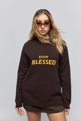 Sweater de punto marrón de tejido liviano y calce relajado, con hombros caídos, cuello redondo y puños y cintura en rib. Cuenta con una estampa tejida en el frente con la frase "Estoy Blessed" en color amarillo.
