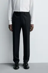 Pantalón de traje regular fit confeccionado en tejido de lana. Presenta bolsillos frontales, bolsillos traseros de vivo con botón y cierre frontal con cremallera y botón.