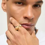 Anillo de aleación de metales bañado en oro 18k con diseño abierto y dos apliques orgánicos en forma de gota en los extremos.