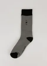 Medias grises de media caña con puntera y talón negros, con detalle de tres líneas verticales en la parte superior y texto en el tobillo. Tejido grueso con felpa.