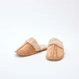 Pantuflas tipo mule color beige, confeccionadas en material efecto gamuza con borde y forro interior de pelo sintético suave.