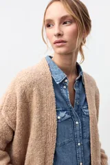 Cardigan de punto abierto en color beige, con diseño de corte holgado, mangas largas con puños acanalados y textura suave.