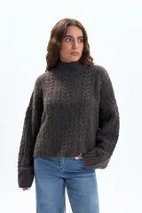 Polera de punto con diseño de textura fantasía, corte crop y cuello alto. Presenta mangas largas con puños acanalados y un calce holgado.