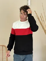 Buzo de cuello redondo con diseño de bloques de color horizontal en blanco, rojo y negro. Presenta mangas largas con puños elásticos y terminación en el ruedo con elástico.