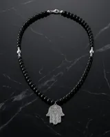 Collar de acero con cuentas de cristal negro y dije central en forma de mano de Hamsa con detalles grabados.