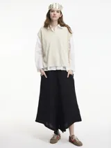 Chaleco de punto color crema con escote en V y textura metalizada. Presenta mini tajos verticales en los laterales.