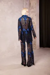 Pantalón de encaje con diseño de flores en color negro sobre base azul, de tiro medio con cintura elástica y corte oxford acampanado.