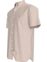 Camisa de manga corta Tommy Hilfiger confeccionada en tejido oxford de algodón. Presenta un diseño a rayas verticales en color naranja y blanco, cuello con botones y logo de la marca bordado en el pecho.