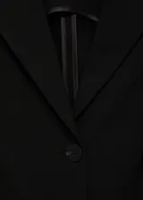 Vestido corto negro tipo chaleco, con cuello solapa, sin mangas y cierre frontal con botones. Diseño entallado al cuerpo.