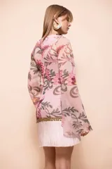 Vestido corto de estilo boho en tono rosa, con estampado floral, escote en V profundo decorado con cuentas y flecos, y mangas largas acampanadas.