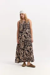Vestido largo sin mangas con escote redondo, silueta amplia y caída fluida, con estampado tipo ikat en tonos negro y beige.