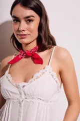 Blusa negra de algodón con tirantes finos, escote en V decorado con encaje y cierre frontal con botones. Presenta un corte holgado con detalles de encaje en el borde inferior.