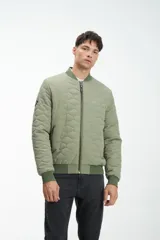 Campera bomber verde con diseño acolchado geométrico, cierre frontal y bolsillos laterales.
