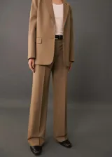 Pantalon de vestir color tostado con diseño wide leg, tiro alto y detalle de pinzas frontales. Cuenta con bolsillos laterales y cierre oculto con botón, gancho y cremallera.