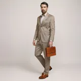 Ambo formal color tostado de corte clásico, compuesto por saco de dos botones con solapas de muesca y bolsillos con solapa, y pantalón recto a juego.