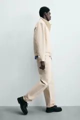 Jeans de hombre color beige claro, tiro medio, corte balloon fit con pierna relajada que se estrecha ligeramente hacia el bajo. Confeccionados en denim rígido de algodón, con cinco bolsillos y cierre frontal de cremallera y botón.
