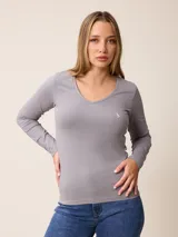 Remera de manga larga color gris, con cuello en V y logo bordado de un pájaro en el pecho.