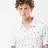 Chomba blanca de piqué con cuello clásico y estampado de palmeras.
