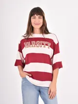 Remera de corte oversize con diseño de rayas horizontales anchas en color bordó y crema. Presenta la palabra 'VARSITY' estampada en el pecho con un patrón de damero.