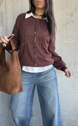 Sweater de tejido de punto color chocolate, con diseño de flores bordadas en relieve, cuello redondo y mangas largas con puños elásticos.