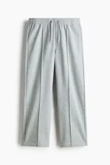 Pantalón jogger de punto de algodón gris melange, de corte relajado y perneras rectas con pliegue frontal cosido. Presenta cintura elástica con cordón ajustable, bolsillos laterales y falsas braguetas decorativas.