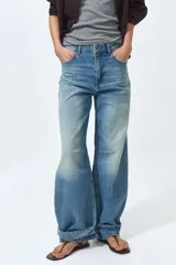Jean de cinco bolsillos en denim de algodón rígido, con piernas maxivolumen de diseño curvo y corte estándar de cadera a muslo, ligeramente ceñidas en el bajo mediante trabilla. Cuenta con cintura de tiro alto, cierre y botón.
