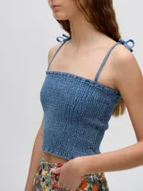 Top crop de tela denim con efecto fruncido, breteles finos ajustables con lazos y diseño entallado al cuerpo.