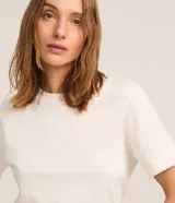 Remera básica de manga corta con vuelta en los puños, cuello redondo y corte recto, de color blanco.