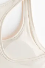 Top deportivo color beige con espalda nadadora, escote redondo y banda elástica inferior.