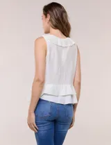 Blusa blanca sin mangas confeccionada en tejido de satén con suave textura arrugada y caída fluida. Cuenta con escote en V con volante en el cuello y ruedo estilo peplum con doble capa de volados superpuestos.