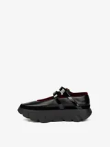 Zapato tipo bailarina de cuero negro con borde de terciopelo rojo, doble tira con hebilla dorada y suela de goma con diseño de neumático.