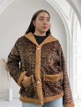 Campera de corderoy con estampado animal print, forrada con piel sintética color beige. Tiene capucha, cierre con botones a presión y bolsillos laterales.