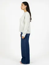 Buzo de punto color beige con cuello redondo y diseño de tejido liso. Presenta mangas largas con puños acanalados y ruedo también acanalado, ofreciendo un corte recto y holgado.