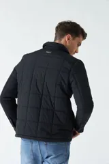 Campera negra de nylon capitoneada, con cuello medio y bolsillos tipo sobre con botón.