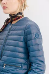 Campera corta negra de nylon rellena con pluma, corte holgado, cuello redondo y bolsillos con cierre.