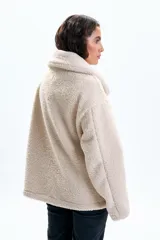 Campera de sherpa color beige, con cuello solapa, cierre frontal completo y bolsillos laterales.