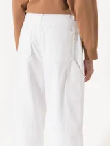 Pantalón de jean blanco, corte wide leg, con detalles de recortes y remaches tipo carpintero.